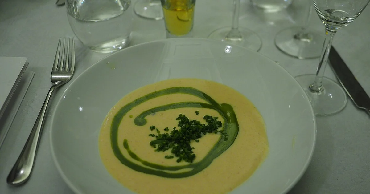 A bowl of cauliflower soup with a snaps glass of akvavit and a glass of white wine (partially shown) served as a starter at a sittning in Helsinki, Finland.
