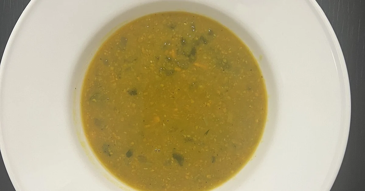 High-quality photograph by Liat Portal showing homemade pea soup prepared by Liat Portal served in a white bowl placed on a dark wooden surface. This image documents a simple vegetable-based soup as part of everyday home cooking within the 