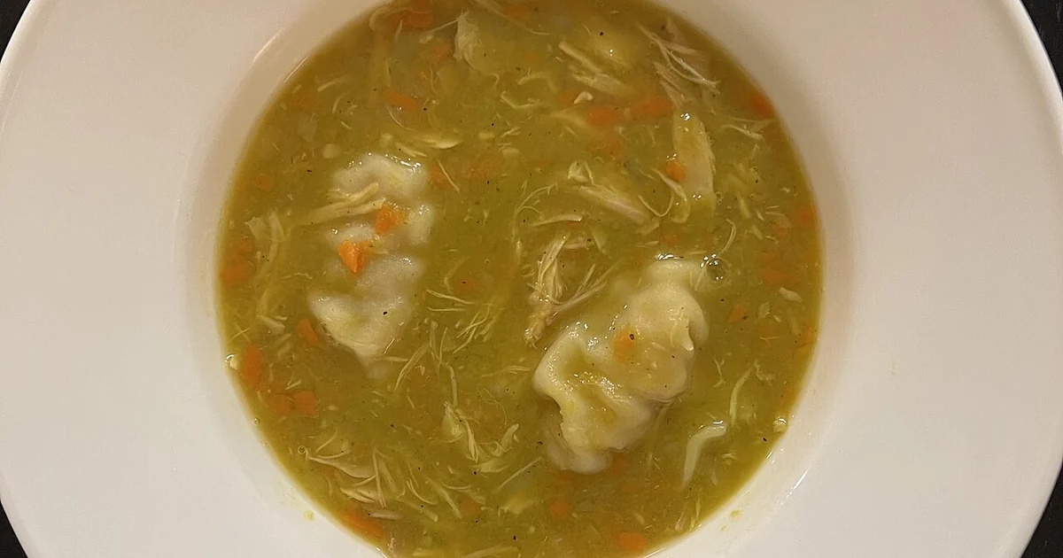 High-quality photograph by Liat Portal showing a homemade pea soup prepared by Liat Portal with a vegetable-based broth, finely chopped carrots and onions, and soft dumplings simmered in the soup. The image captures a simple home-cooked com