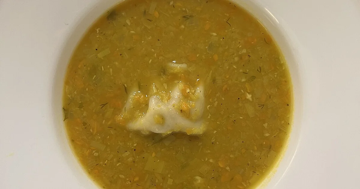 High-quality photograph by Liat Portal showing a bowl of homemade red lentil soup prepared from scratch, containing sweet potato, celery, shallot, onion, leeks, chickpeas, and garlic, topped with a dumpling. This image documents home cookin